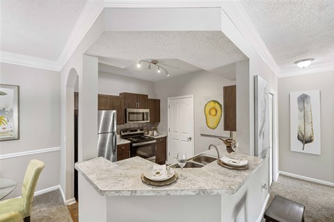 a kitchen with a marble counter top and a stainless steel refrigerator