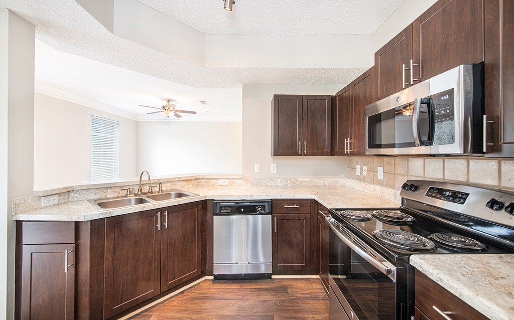 an empty kitchen with wooden cabinets and stainless steel appliances