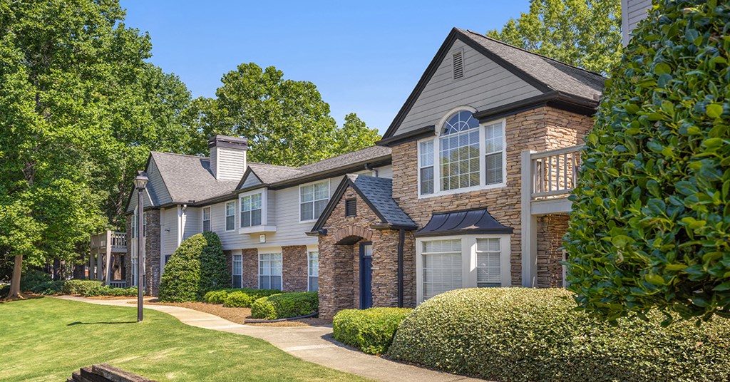 a brick house with blue shutters and a sidewalk