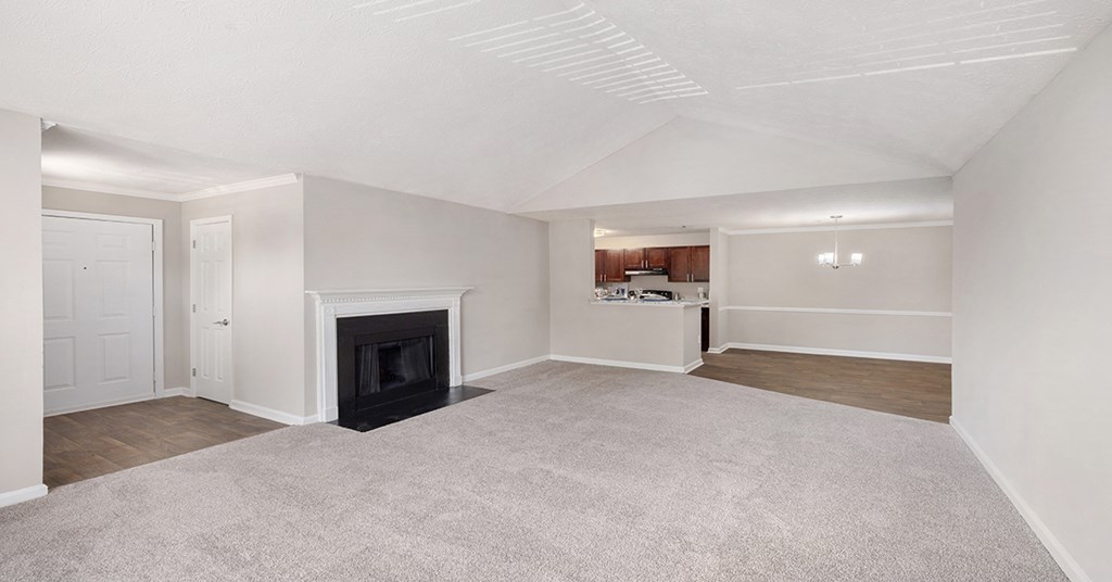 an empty living room with a fireplace and a kitchen