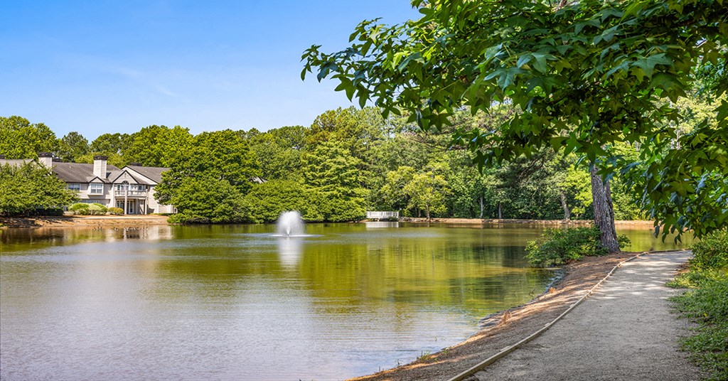a lake with a fountain and a house in the background
