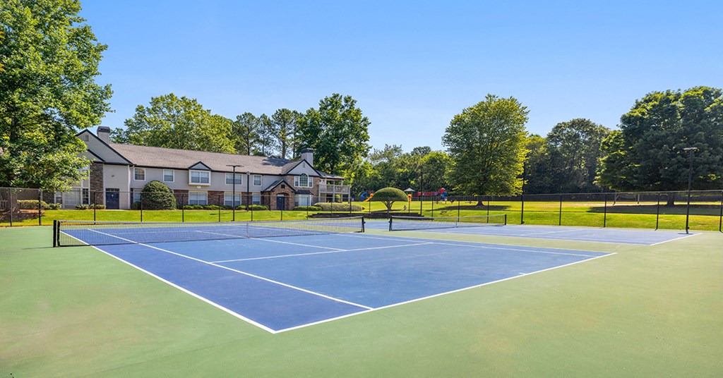 a tennis court with a house in the background