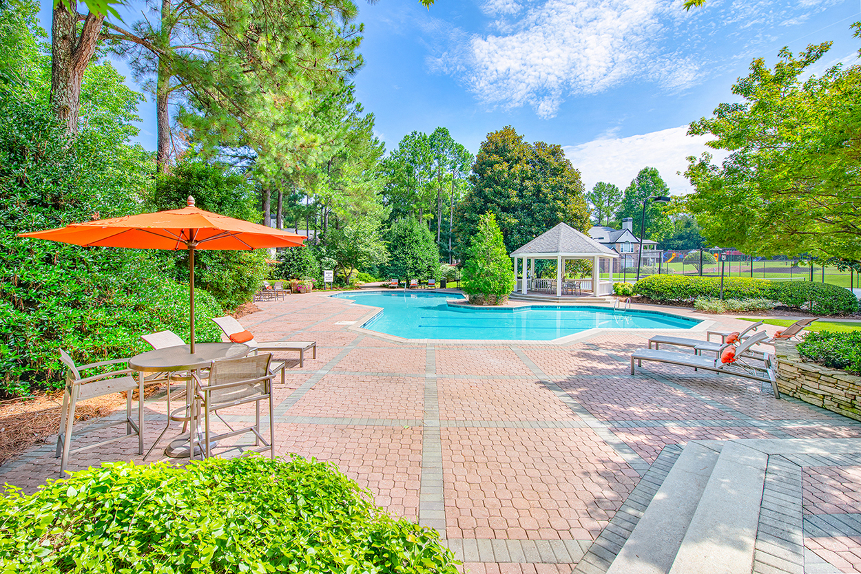 a swimming pool with an umbrella and patio furniture