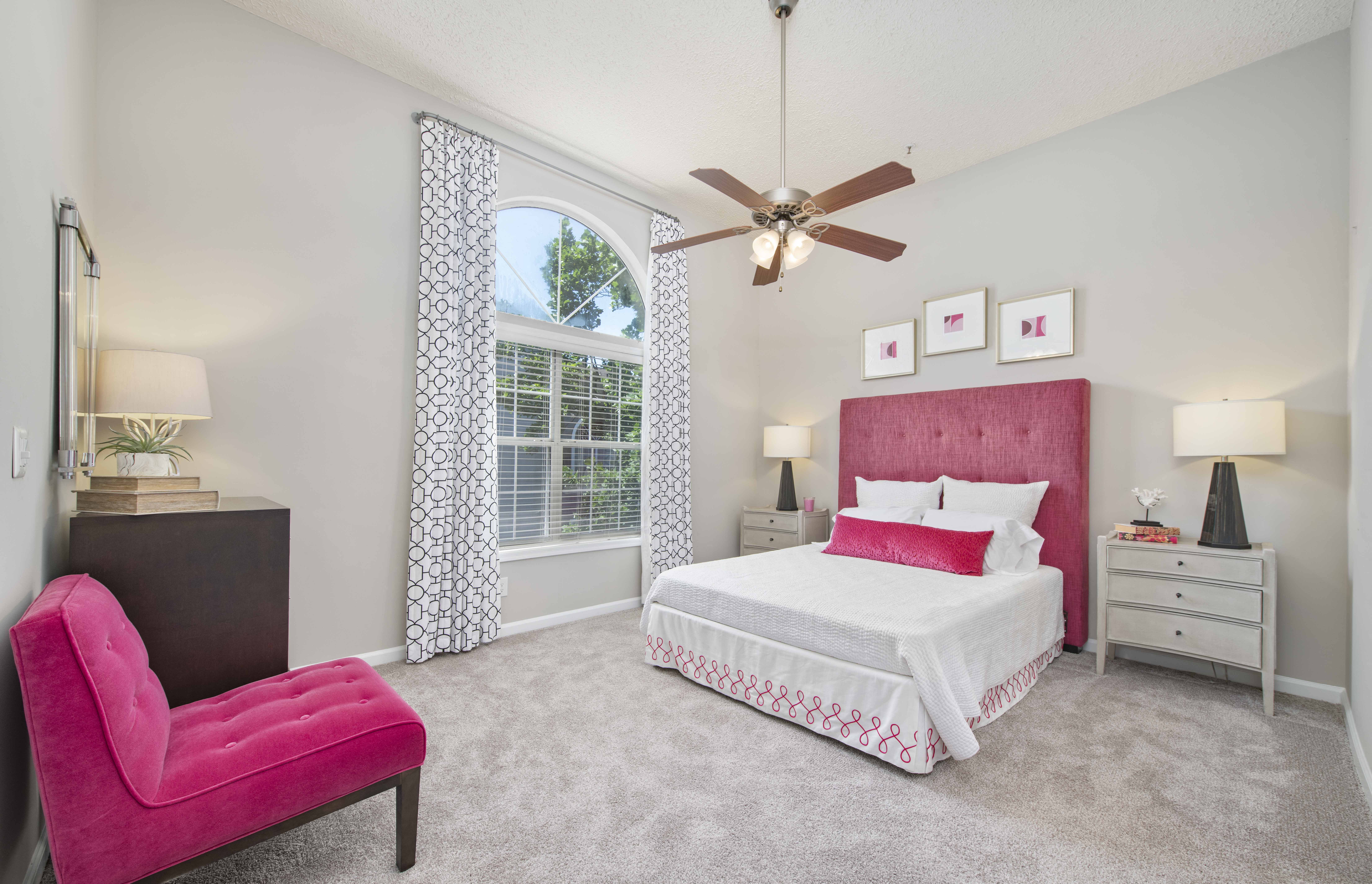 a bedroom with a bed and a chair and a ceiling fan