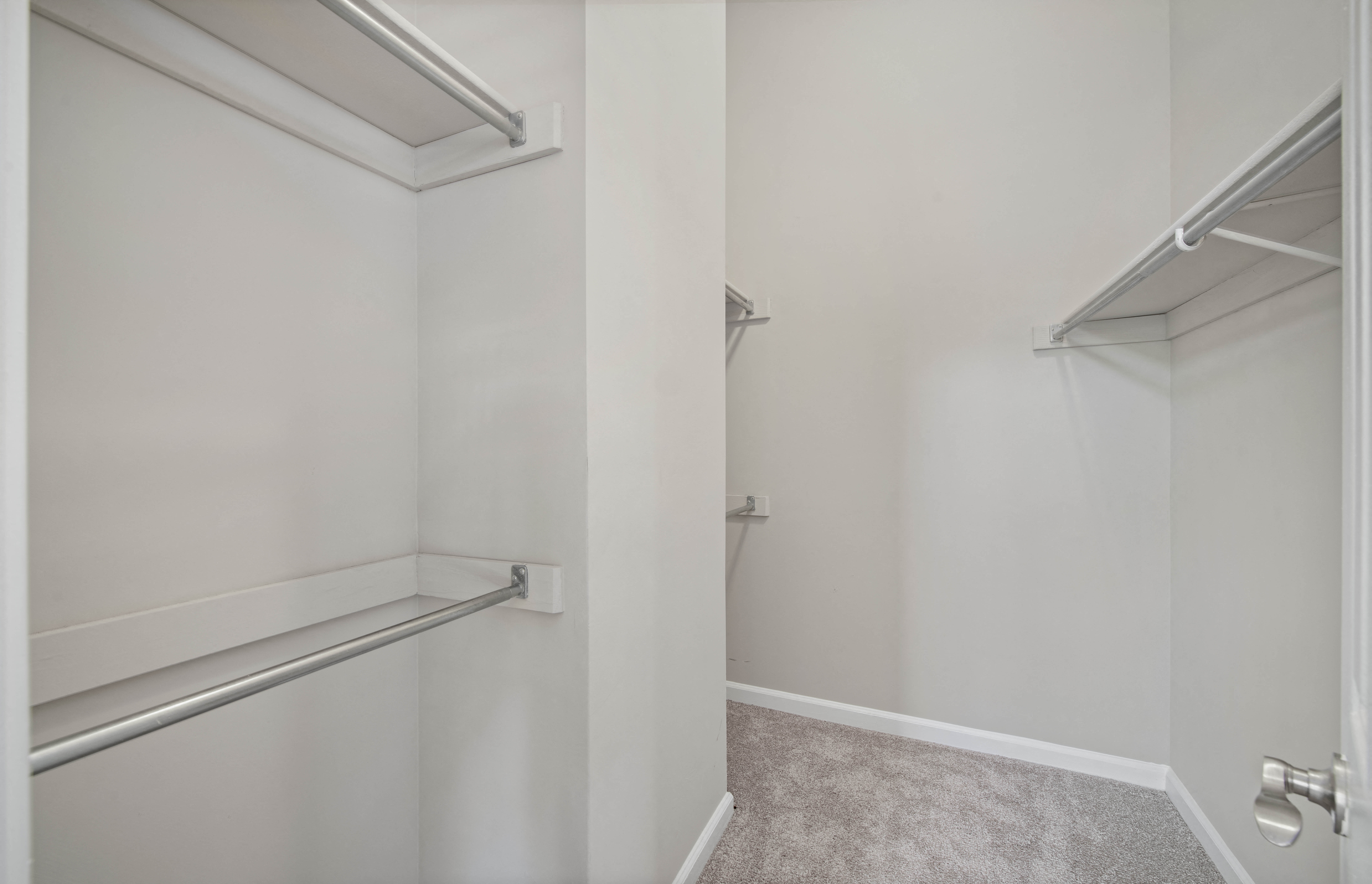 an empty closet in a home with white walls and a gray carpet