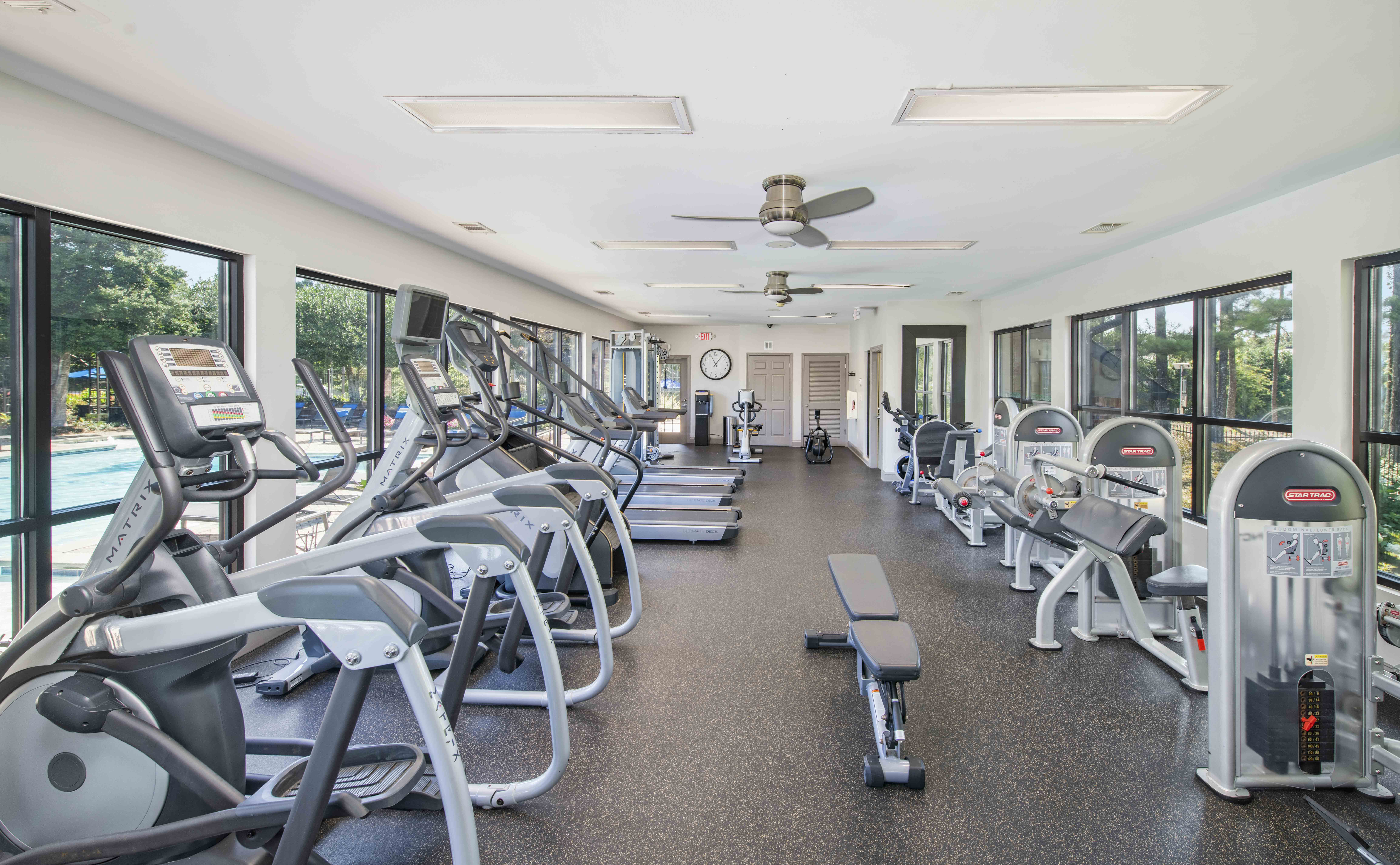 a gym with cardio equipment and windows