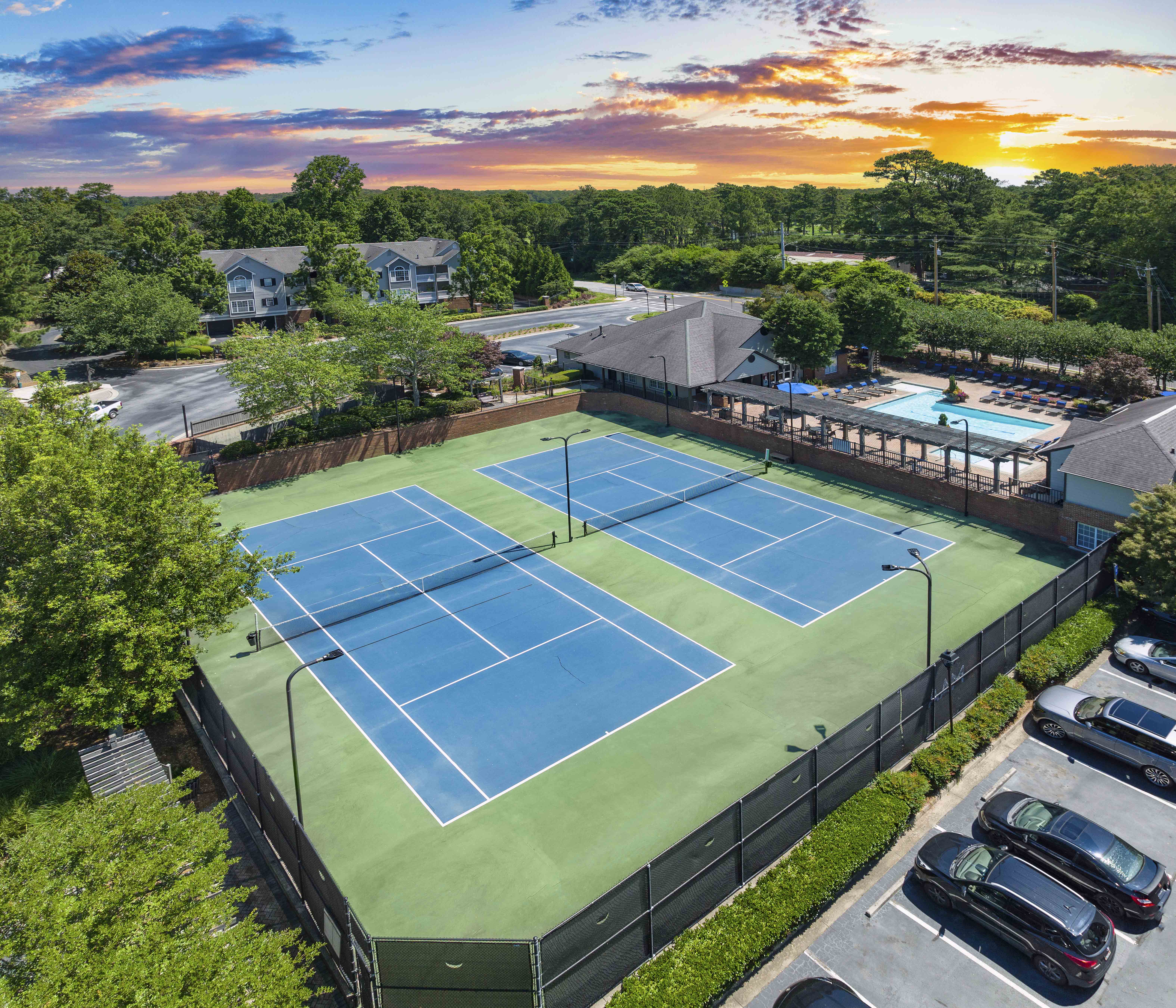an aerial view of a tennis court and a pool at sunset