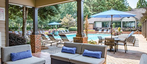 a patio with a pool and chairs and umbrellas