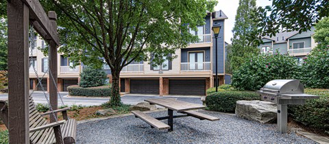a patio with a picnic table and a grill in front of an apartment building