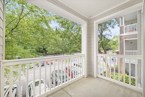 a balcony with a white railing and a view of trees