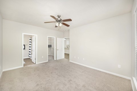 a spacious living room with carpet and a ceiling fan