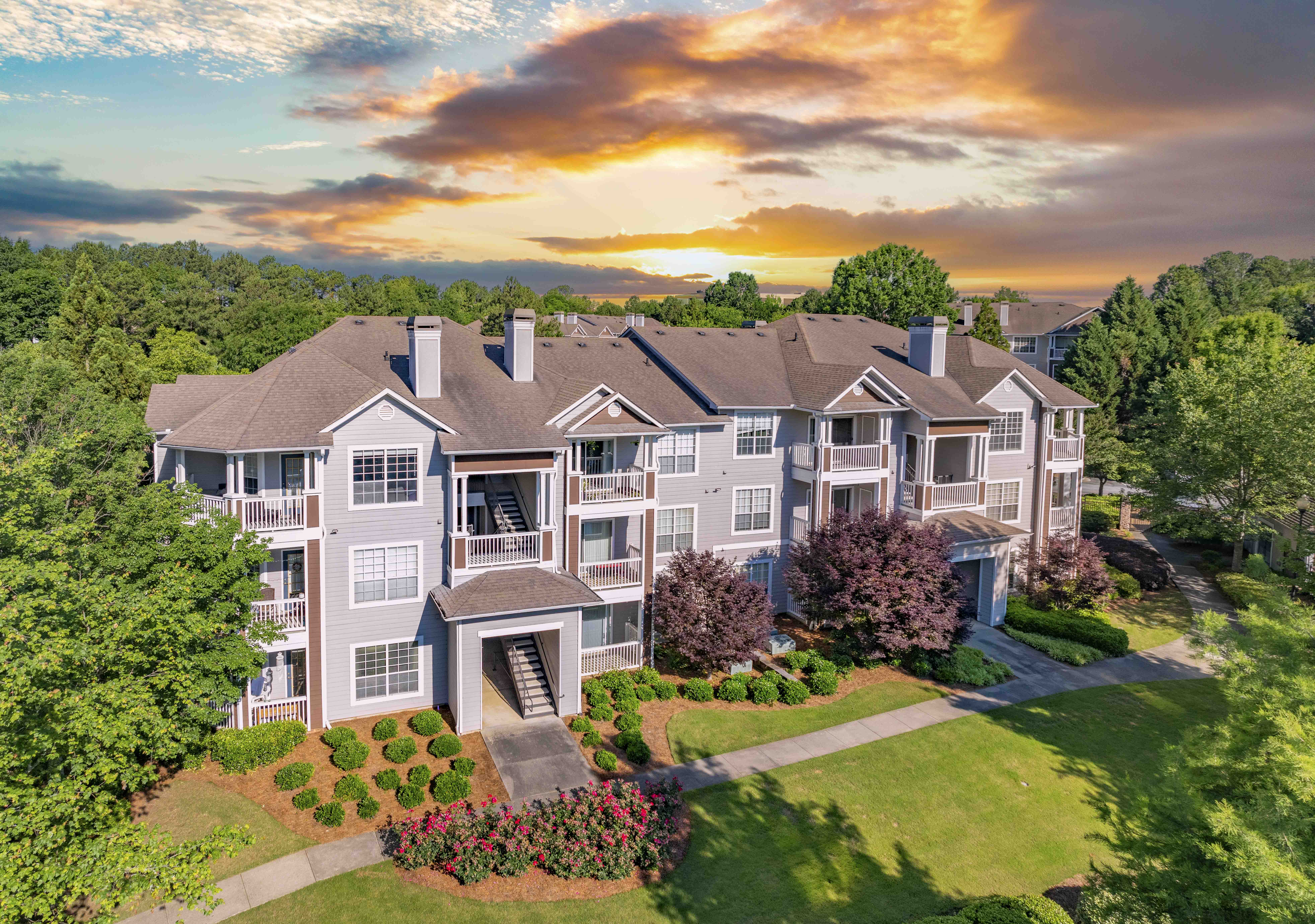 an aerial view of an apartment building with a sunset in the background