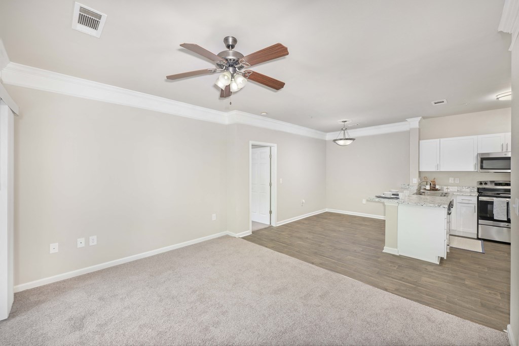 a living room with a ceiling fan and a kitchen