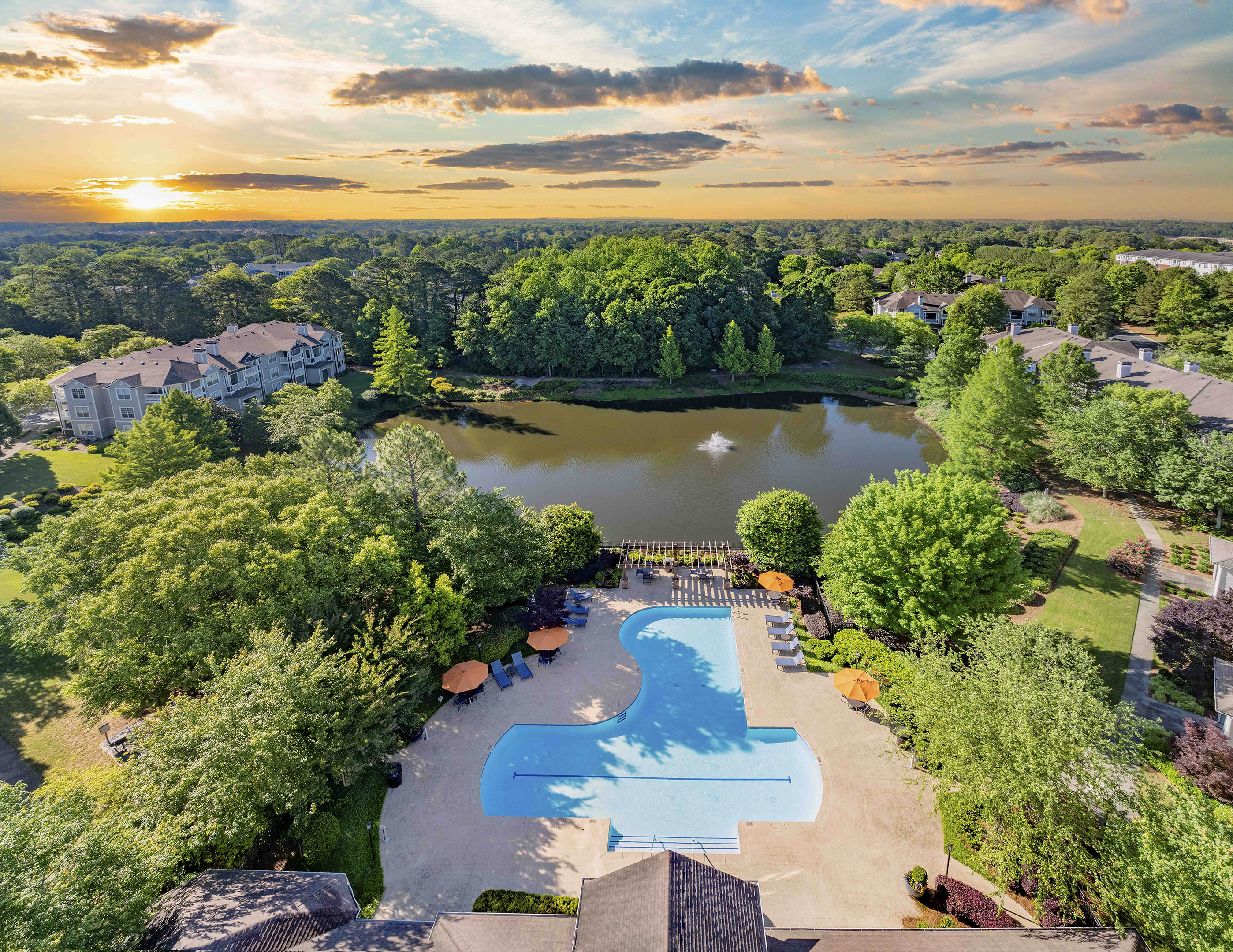 an aerial view of a swimming pool and a lake at sunset