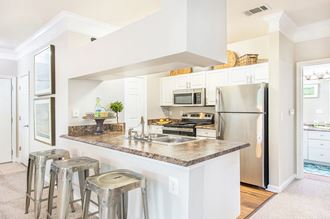 a kitchen with stainless steel appliances and a counter with bar stools
