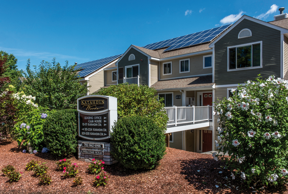 a house with a sign and flowers in front of it