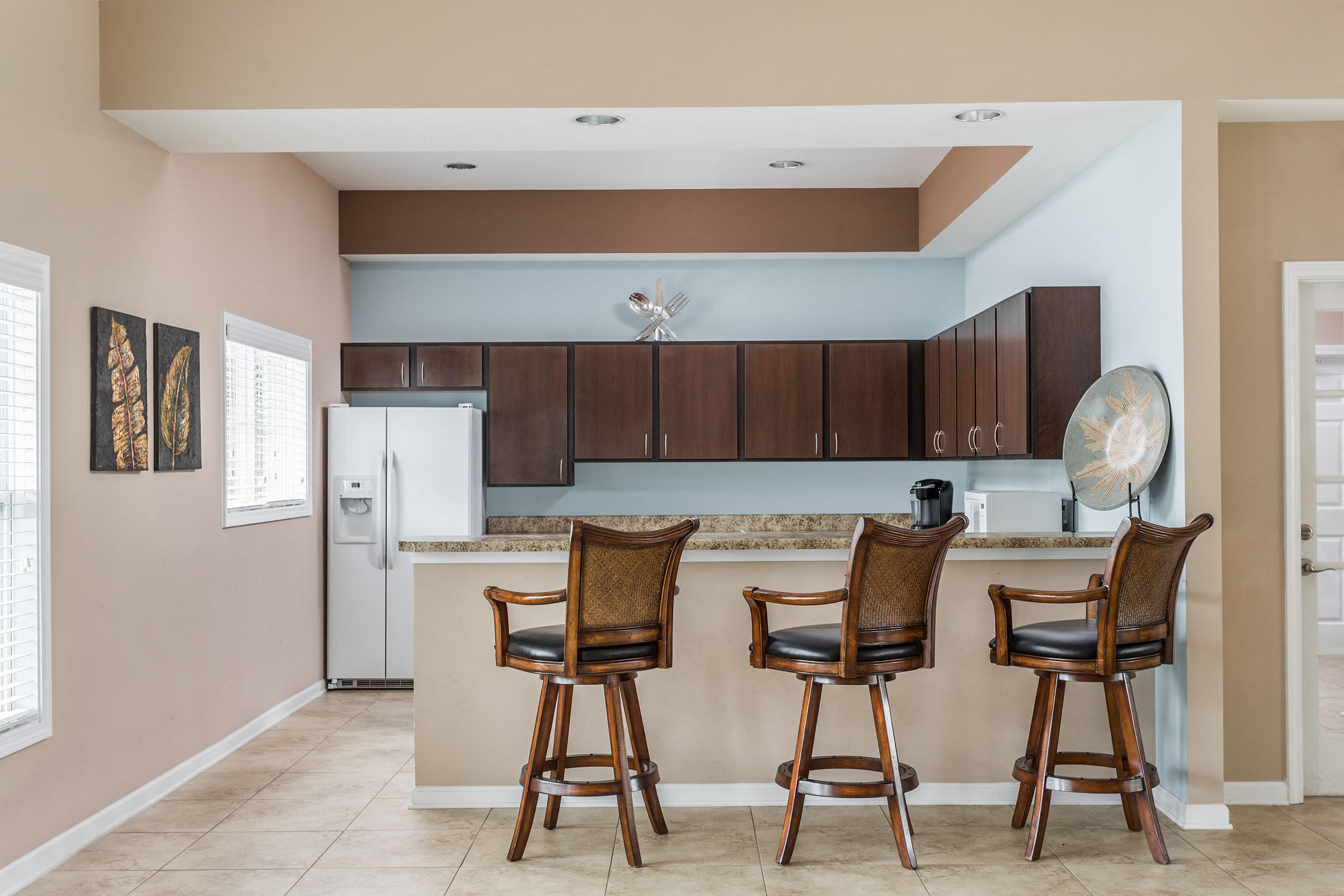 A kitchen with brown chairs and brown cabinets.