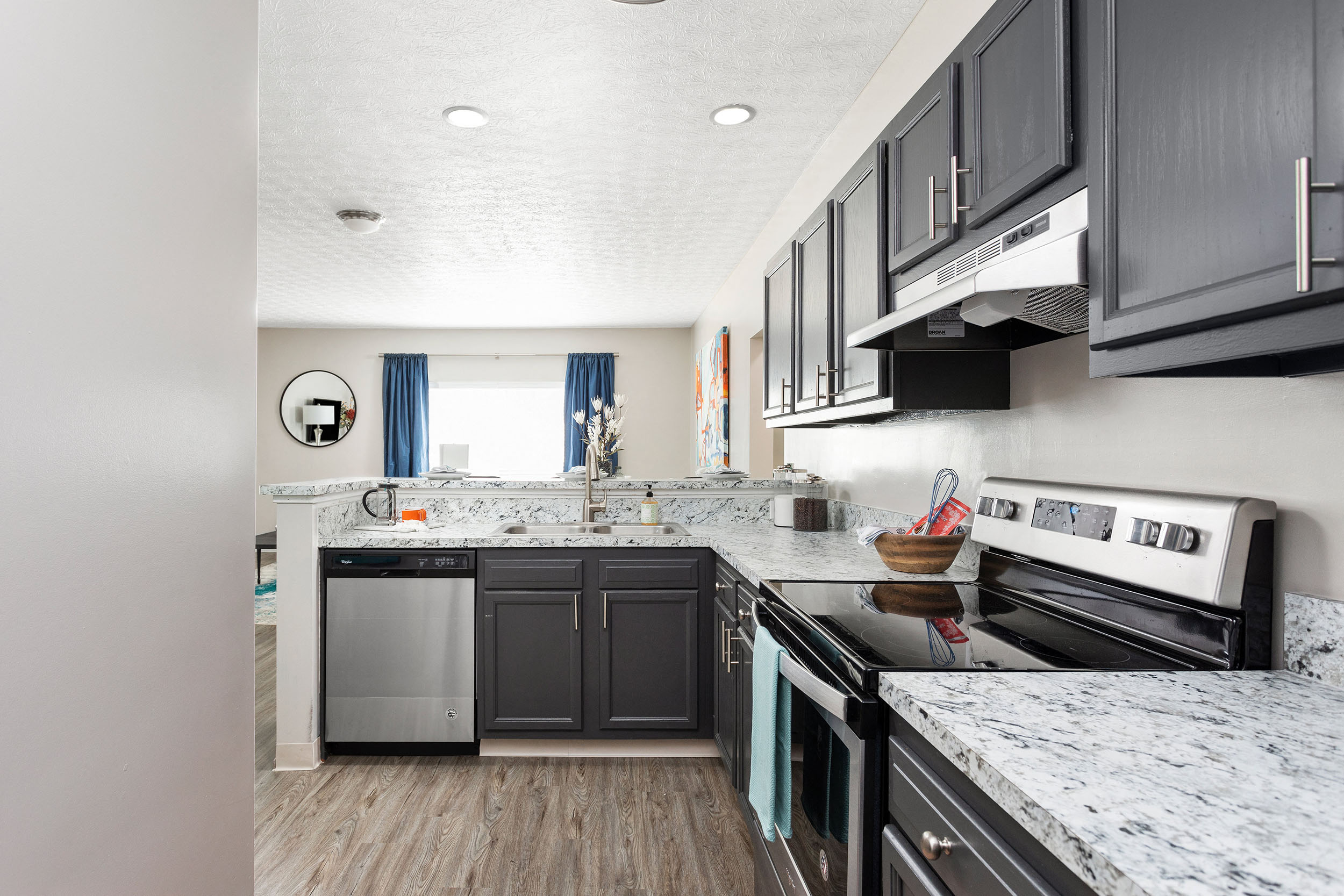A modern kitchen with dark cabinets and a marble countertop.