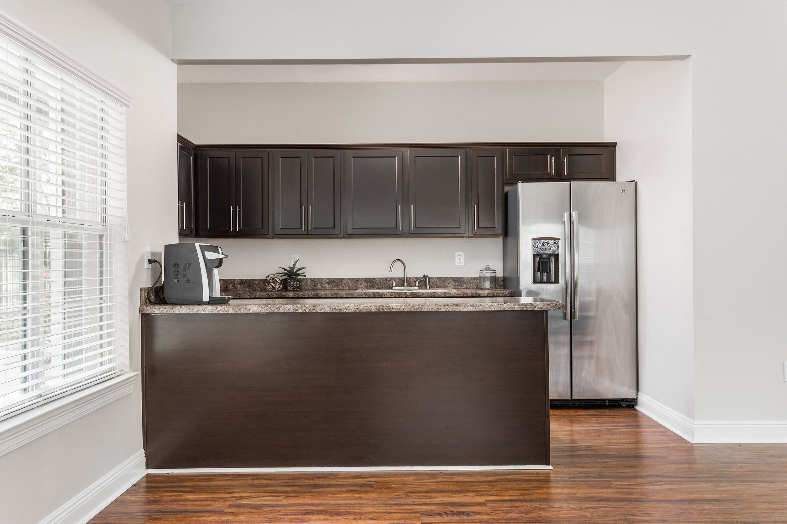 A kitchen with dark brown cabinets and a stainless steel refrigerator.