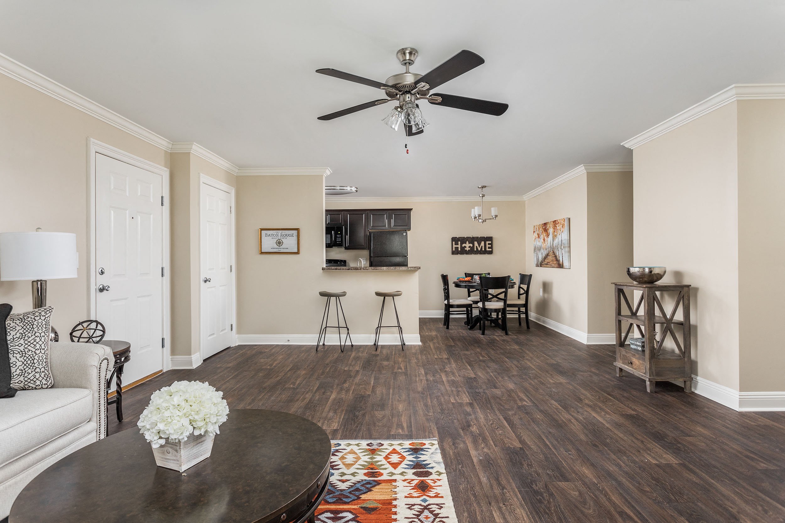 A living room with a ceiling fan and a dining table with chairs.