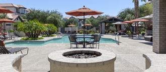 a patio with a fire pit and tables with umbrellas