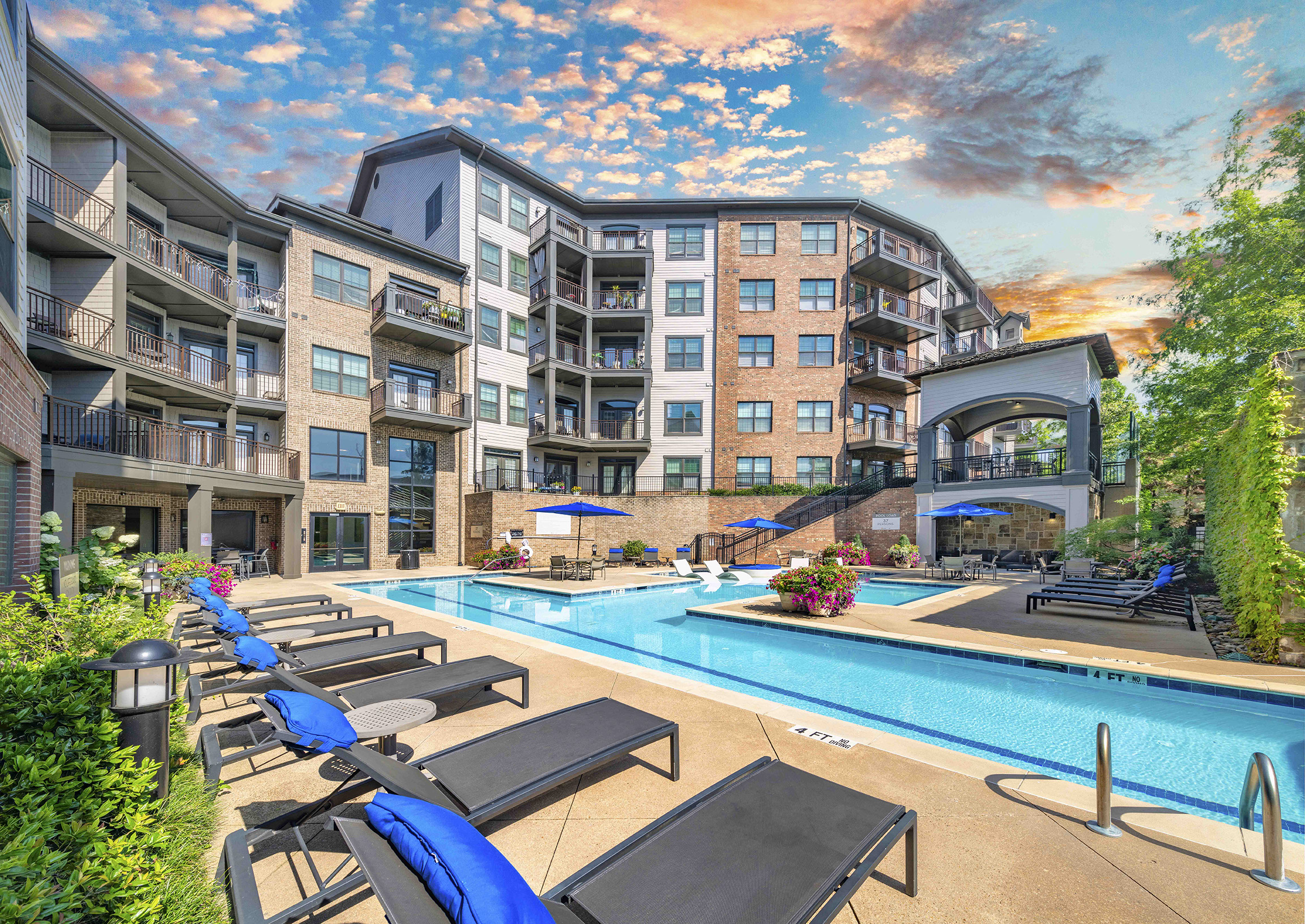 an outdoor pool with lounge chairs and a building in the background