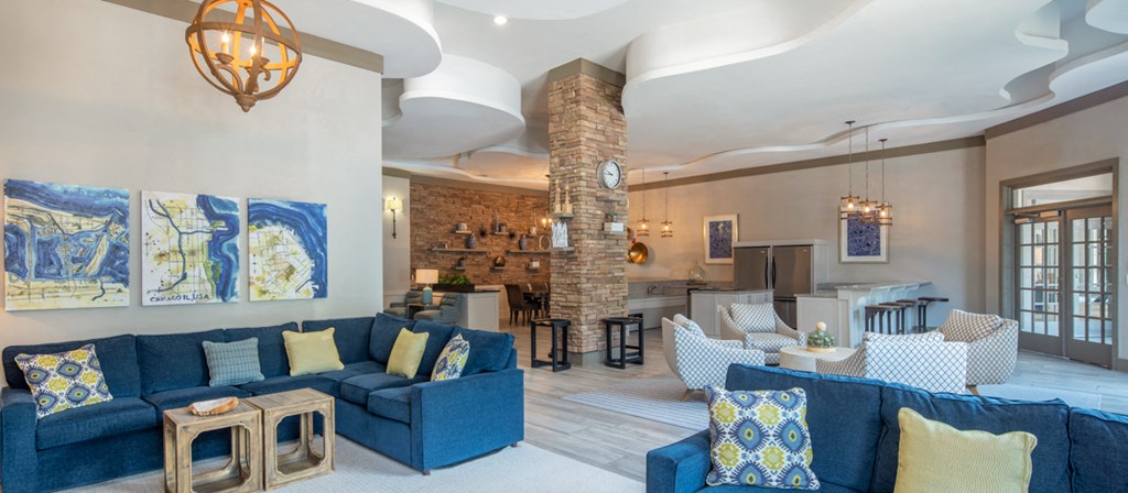 a living room with blue couches and chairs and a kitchen