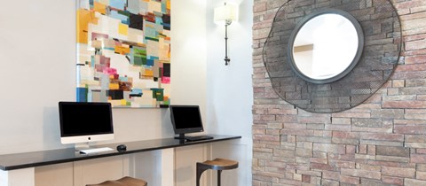 an oval mirror hangs above a desk with two computers on it