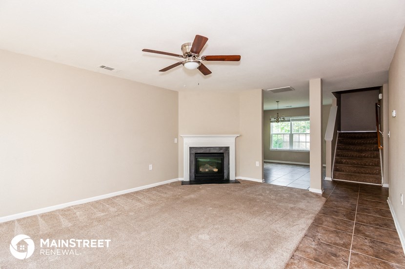 a living room with a fireplace and a ceiling fan
