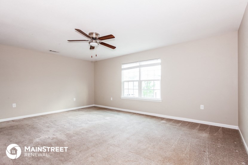 the master bedroom is spacious and clean with a ceiling fan