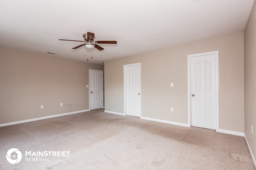 a living room with two doors and a ceiling fan