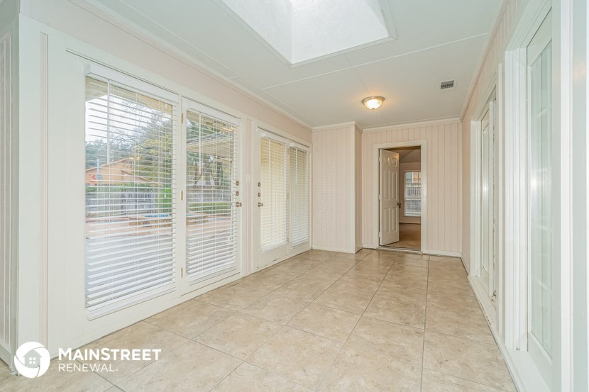 a hallway with windows and a tile floor and a door to a hallway