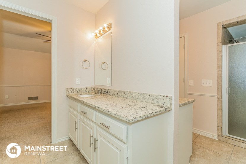 the master bathroom has a granite counter top and white cabinets