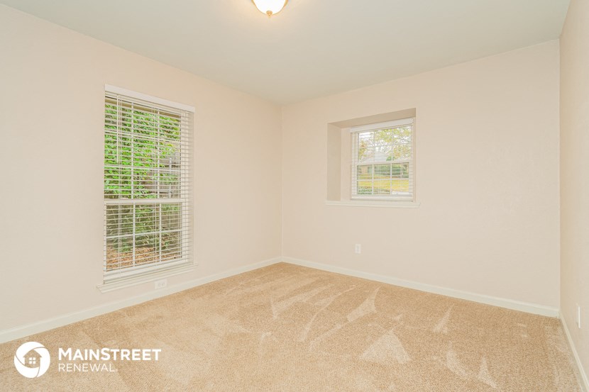 the spacious living room with two windows and beige carpeting