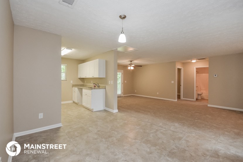 the spacious living room and kitchen with white cabinets and tile flooring