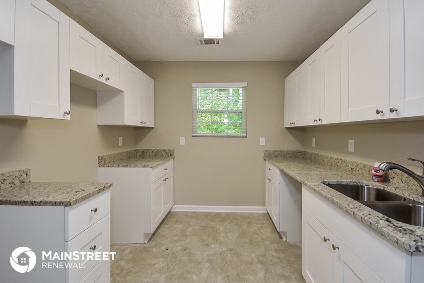 a kitchen with white cabinets and granite counter tops and a sink