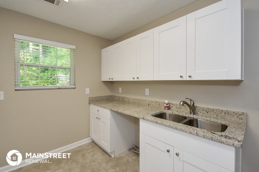 a kitchen with white cabinets and granite counter tops and a sink