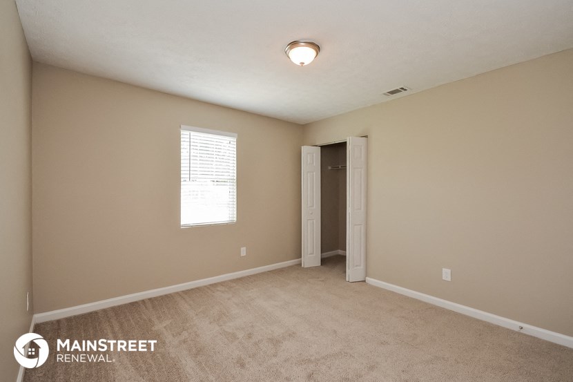 the spacious living room with carpeting and a door to the hallway
