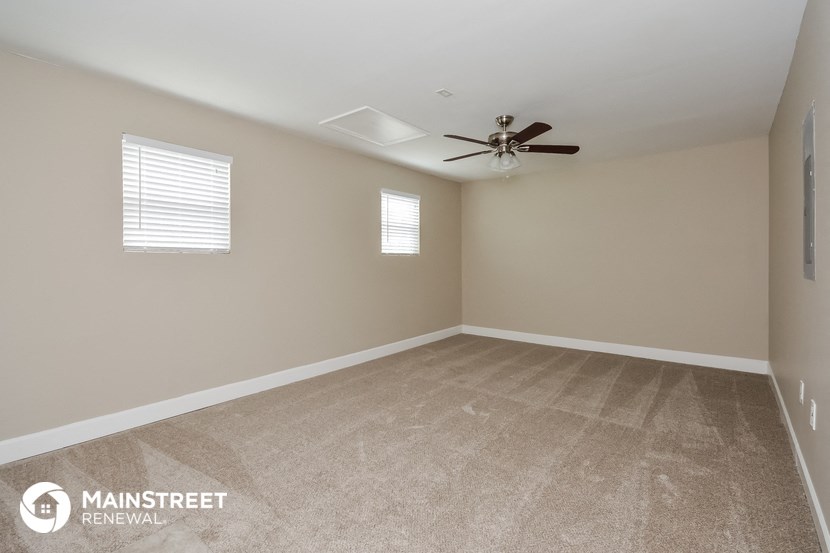 an empty room with a ceiling fan and a window