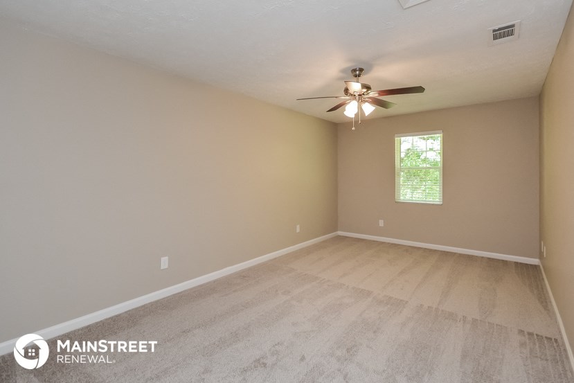 the spacious living room with hardwood floors and a ceiling fan