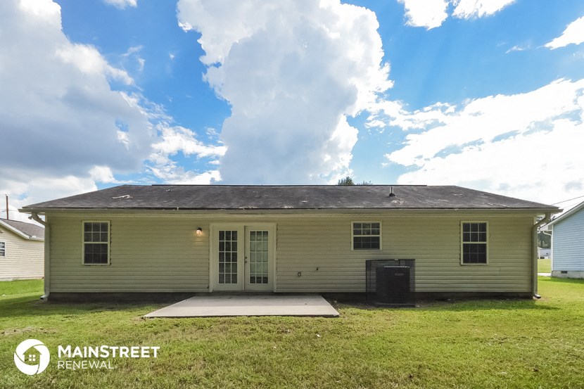 front view of a yellow house with a yard and a cloudy sky