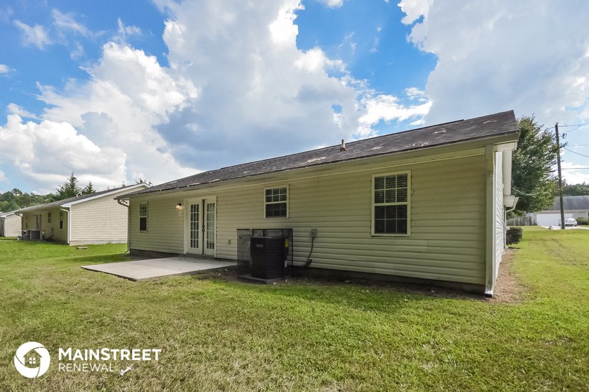 the front of a yellow house with a yard and a backdoor