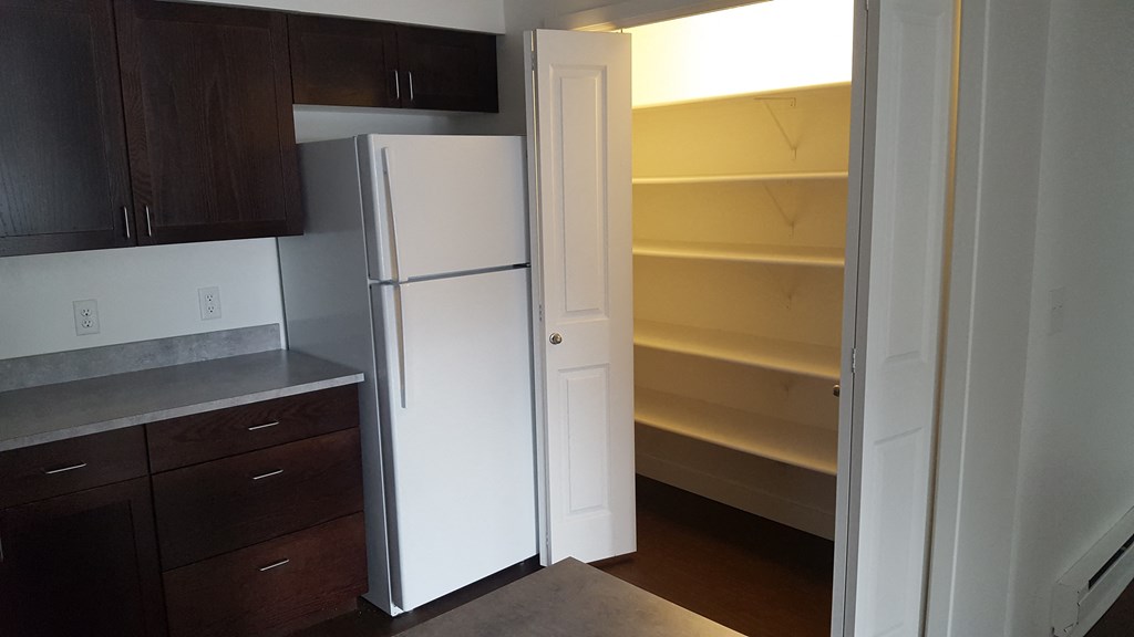 an empty kitchen with a white refrigerator and wooden cabinets
