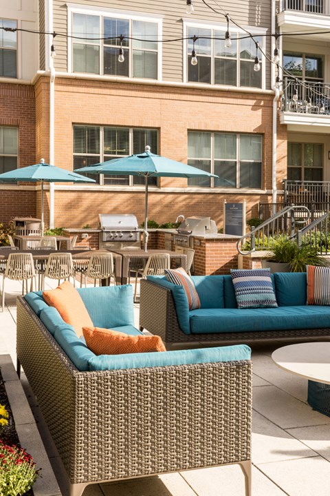 a patio with couches and tables and umbrellas in front of a building