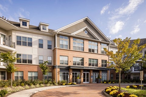 an exterior view of an apartment building with a driveway and trees