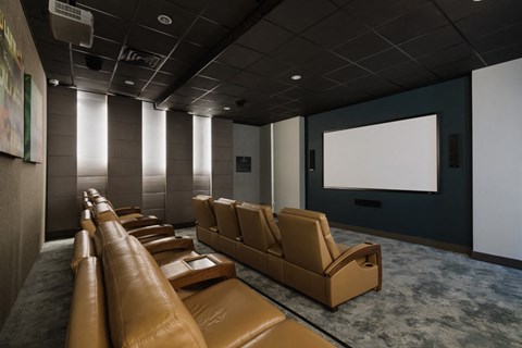 a large screening room with brown leather chairs and a projector screen