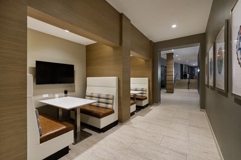 a long corridor with benches and a table and a tv in a hotel room