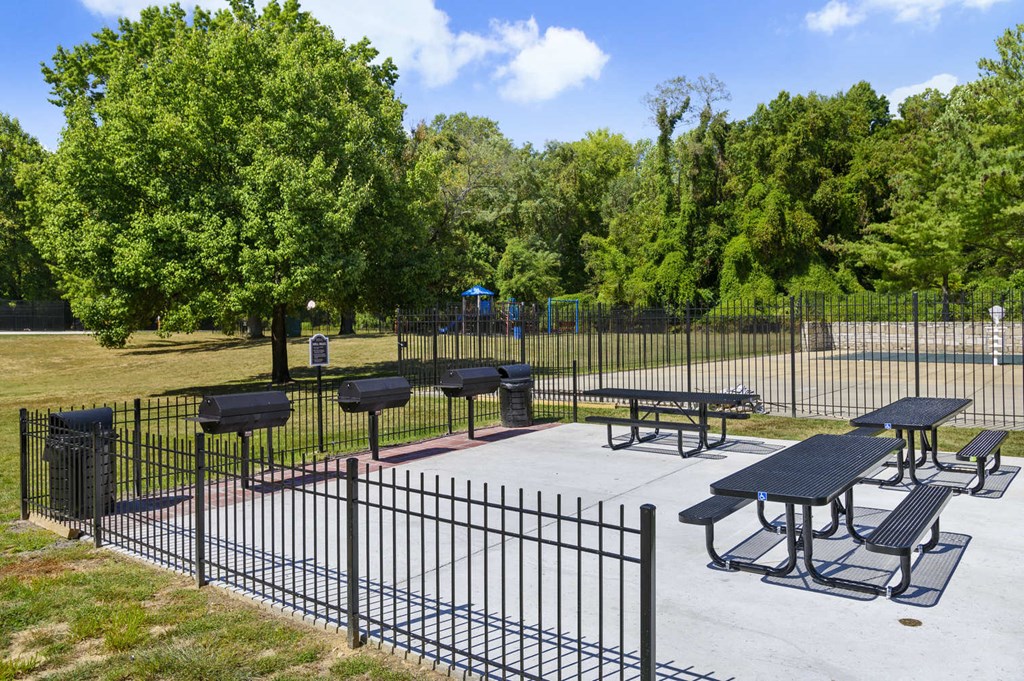 a park with picnic tables and a fenced in area