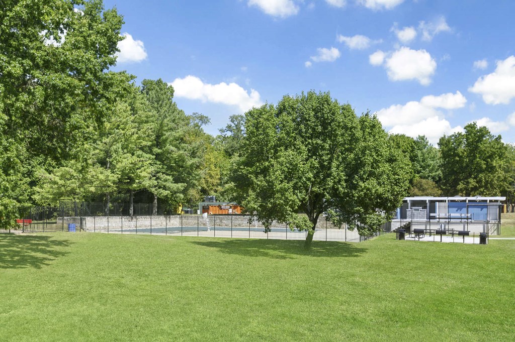 a park with trees and a fence and a truck in the background