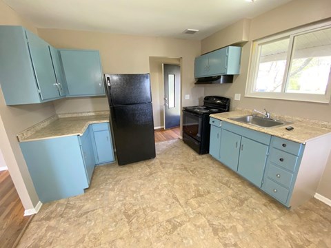 an empty kitchen with blue cabinets and a black refrigerator